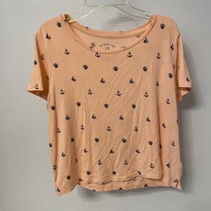 Light pink/peachy color. Graphic tee. Comes to waist/pant line. Sort of cropped